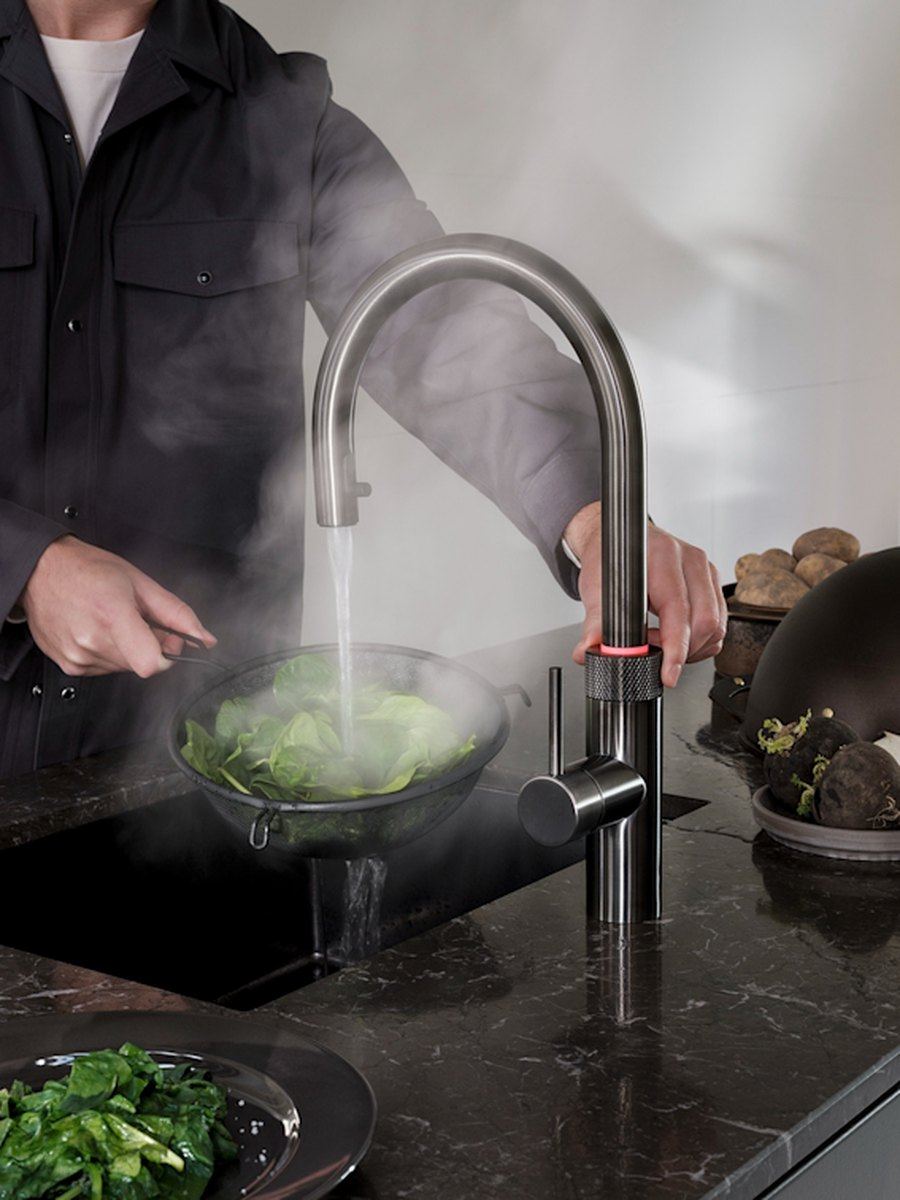 Quooker Armatur gibt kochendes Wasser über ein Sieb mit Gemüse ab